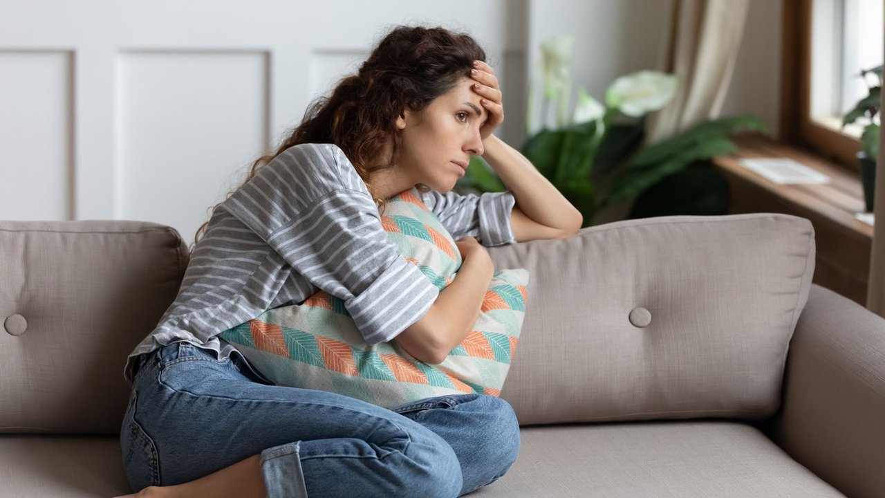 Frau sitzt auf Sofa und macht sich Sorgen