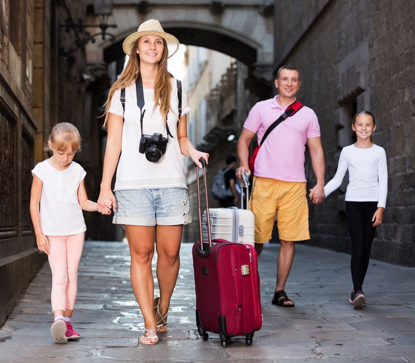 Touristische Familie mit Koffern läuft durch eine enge Gasse