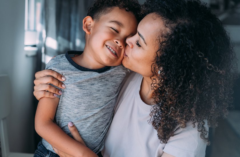 Quallen-Eltern: Mama küsst und umarmt ihr lachendes Kind