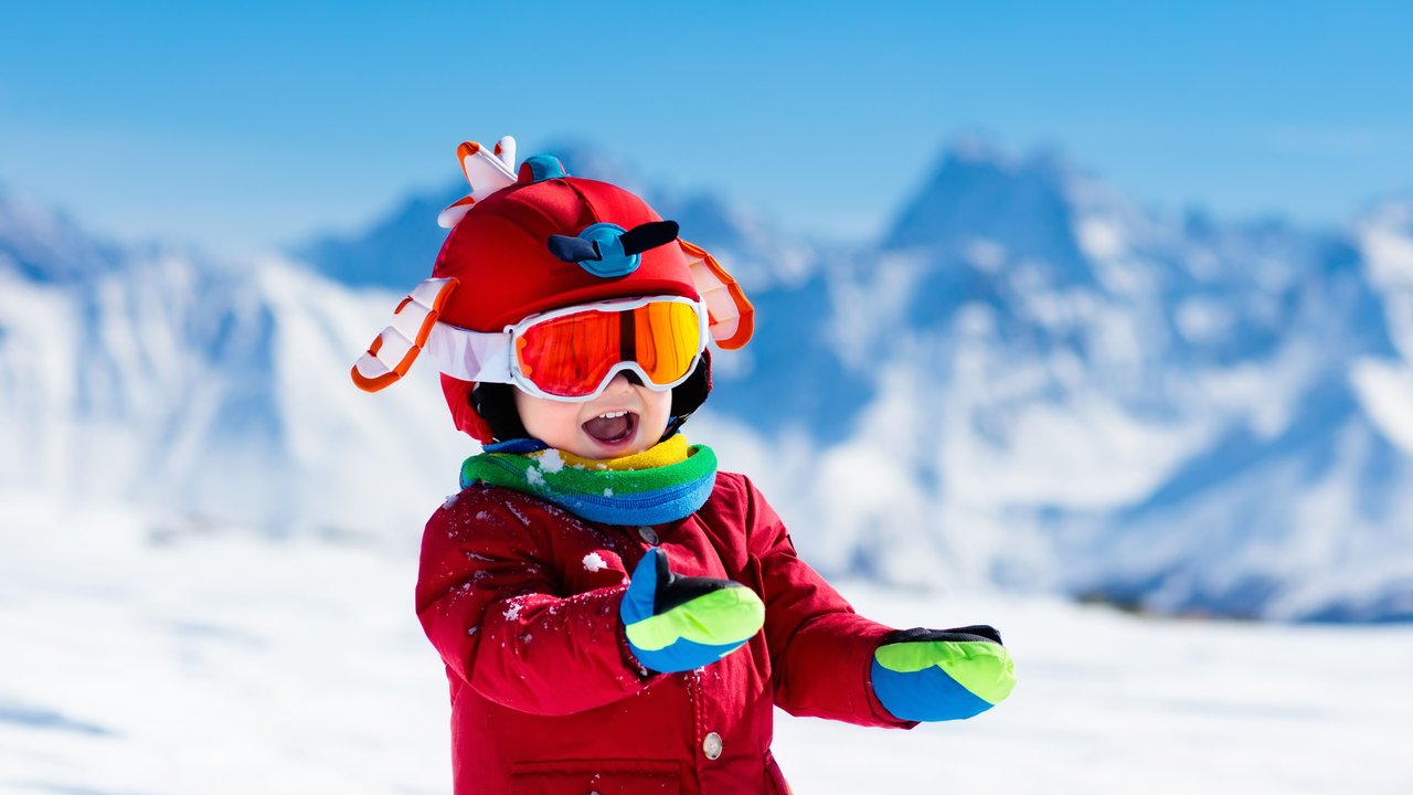 Kleiner Junge mit Skihandschuhen im Schnee