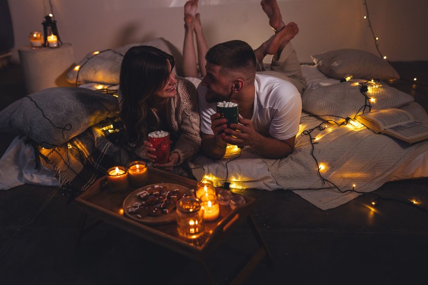 Paar bei einem gemütlichen Weihnachtsabend mit Keksen, Kakao und Lichterketten