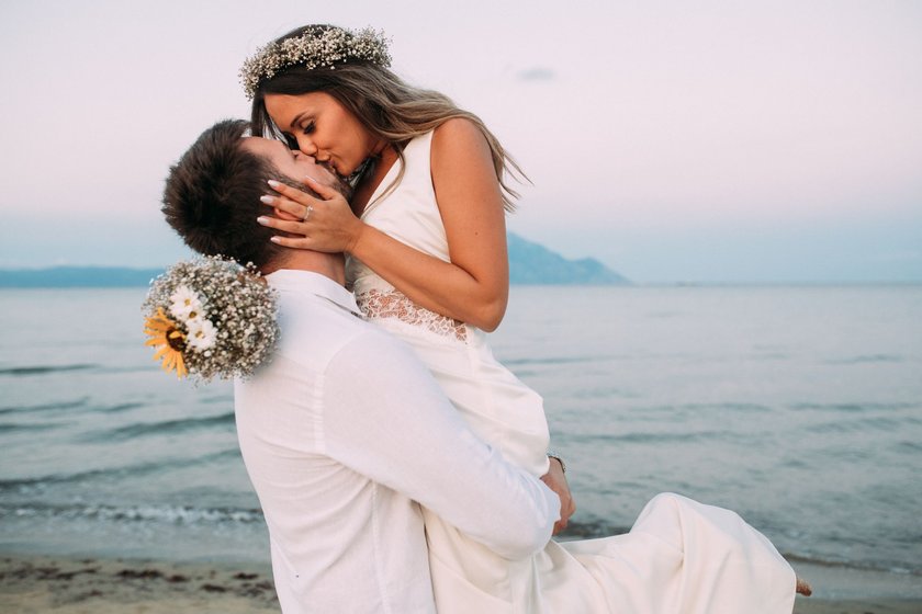Junges verheiratetes Pärchen küsst sich am Strand