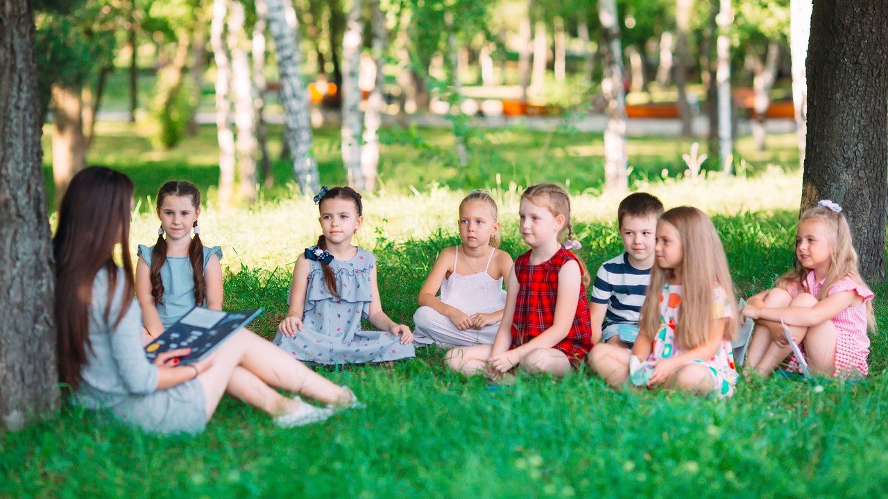 Hitzefrei in der Schule: Kinder machen es sich mit der Lehrerin unterm Baum gemütlich