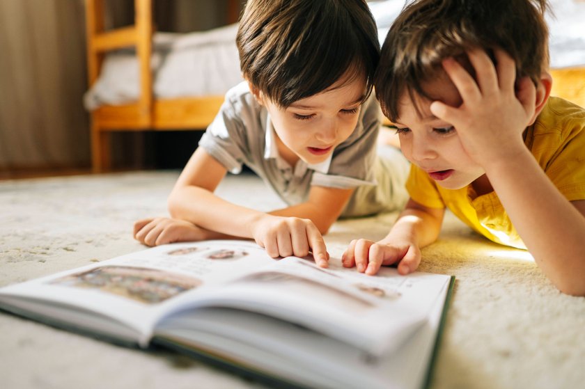 Brüder lesen zusammen ein Buch in ihrem gemeinsamen Kinderzimmer.