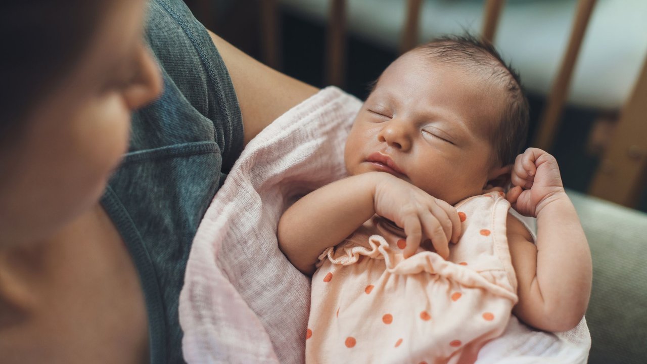 Glückwünsche zur Geburt Mädchen: Mama hält Neugeborenes im Arm 