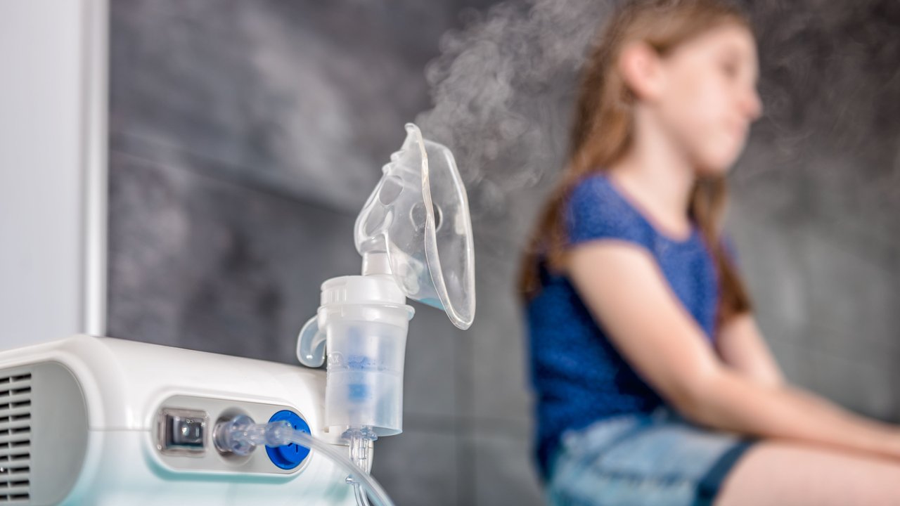 Mädchen sitzt neben seinem Inhalatiosngerät