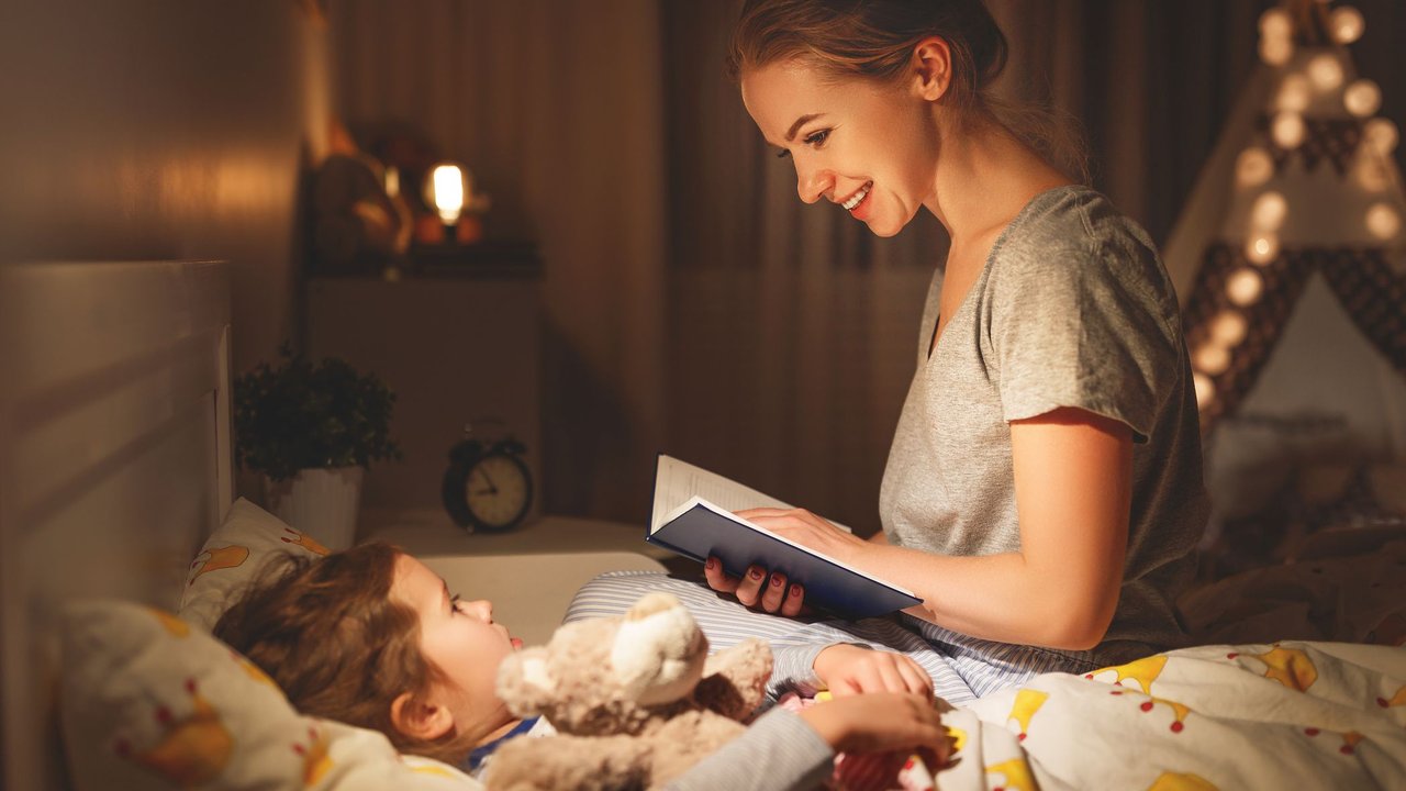 Mutter liest ihrer Tochter als Einschlafritual eine Gutenachtgeschichte vor.