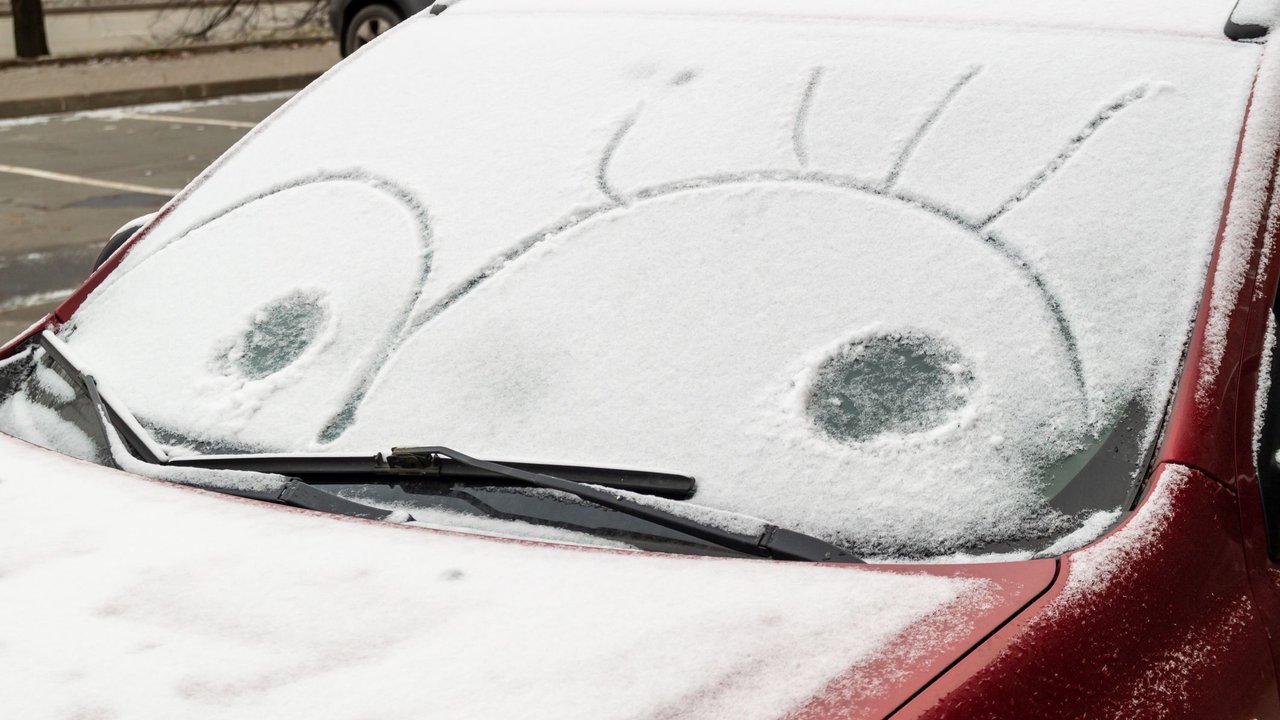 eyes drawn on the snow-covered windshield of a car