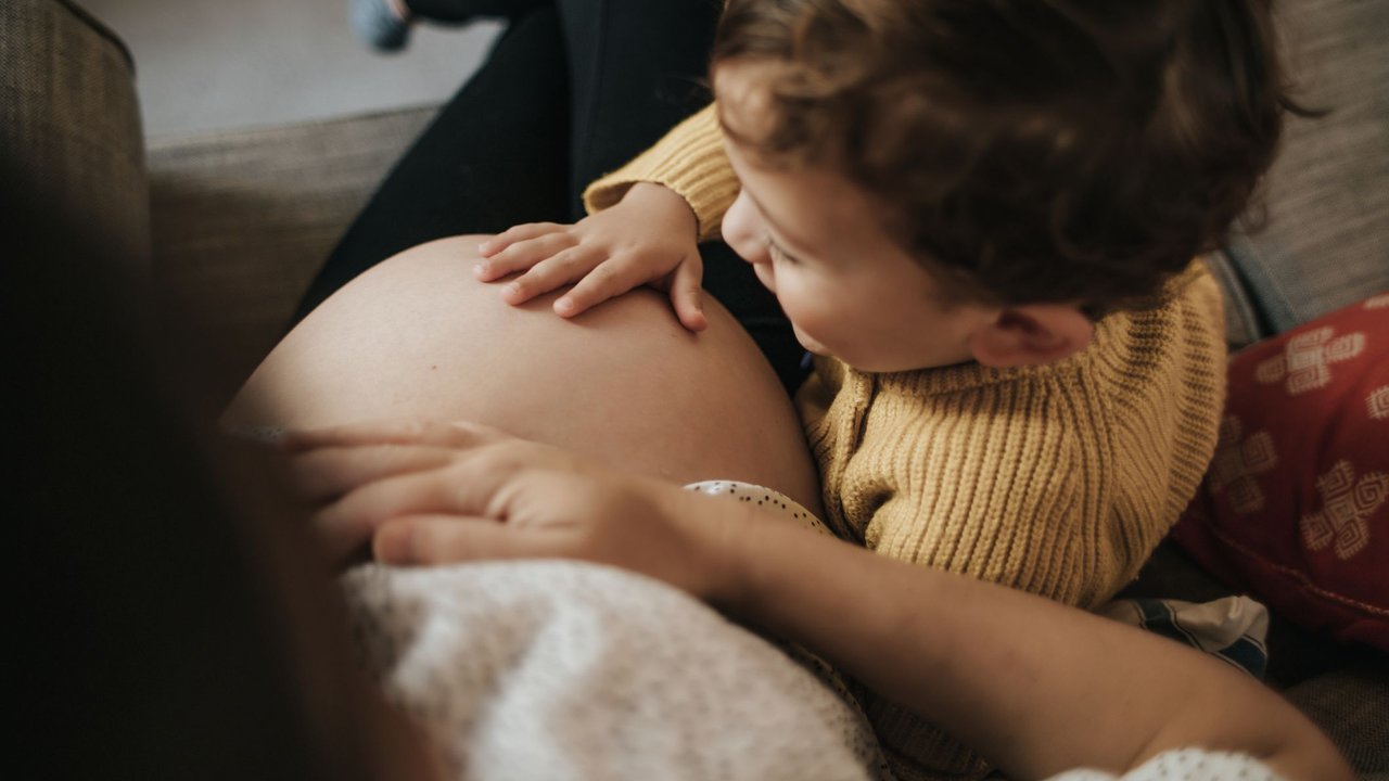 Zweite Schwangerschaft: Kleinkind streichelt Mamas Bauch