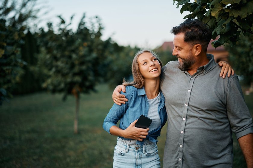 Erfolgreiche Kinder: Papa und Teenager-Tochter laufen Arm in Arm