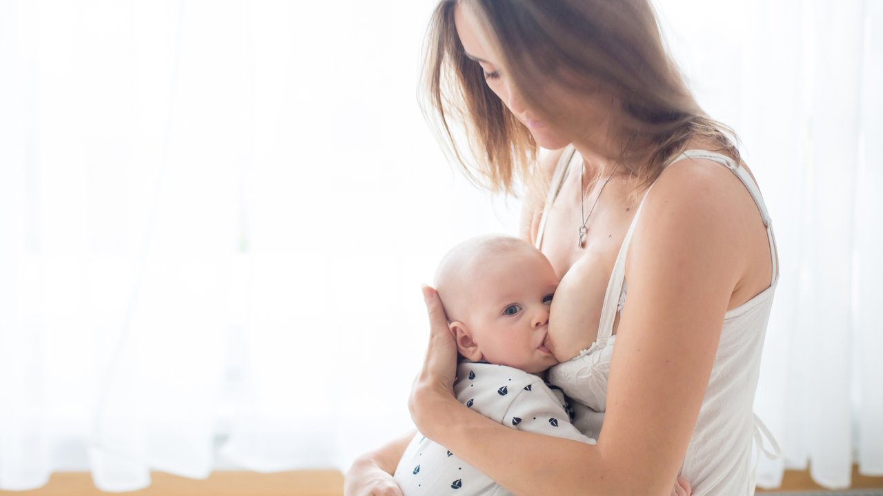 Bergauf stillen: Baby trinkt aufrecht an Mamas Brust