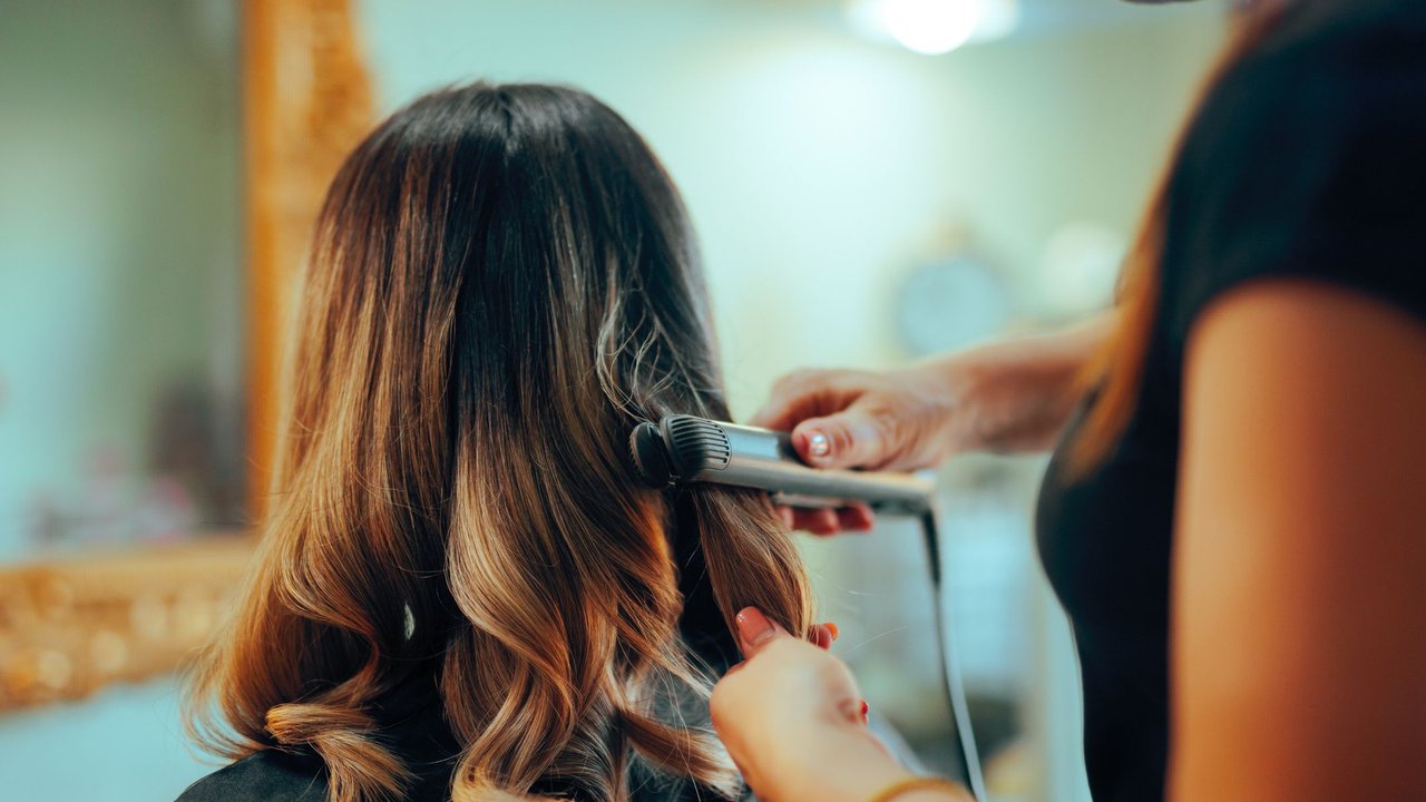 Eine Frau sitzt beim Friseur und bekommt Locken gestylt