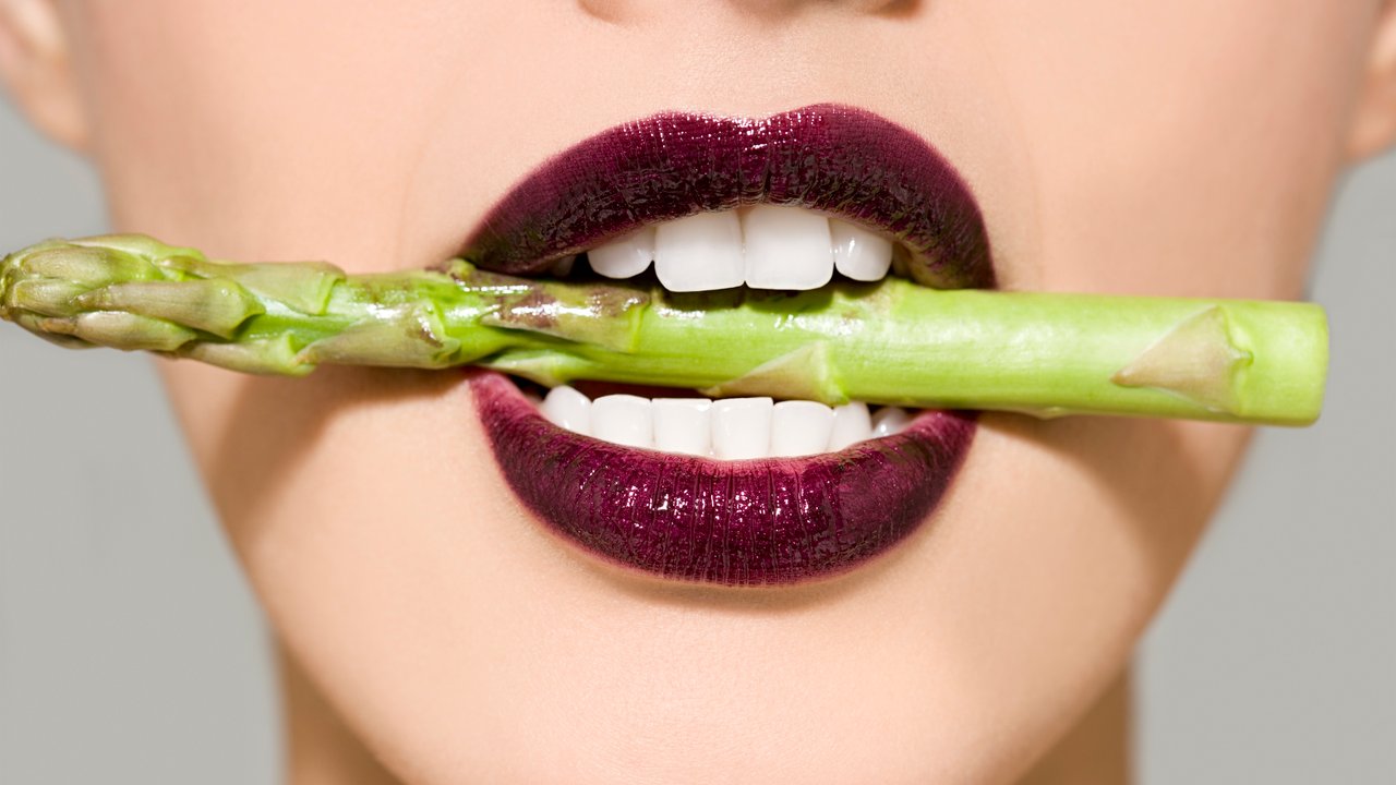 Woman in asparagus in her mouth