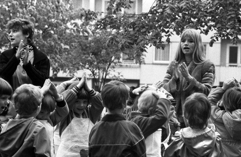  Kindergartenkinder spielen mit ihren Erziehern im Freien, Berlin 1983