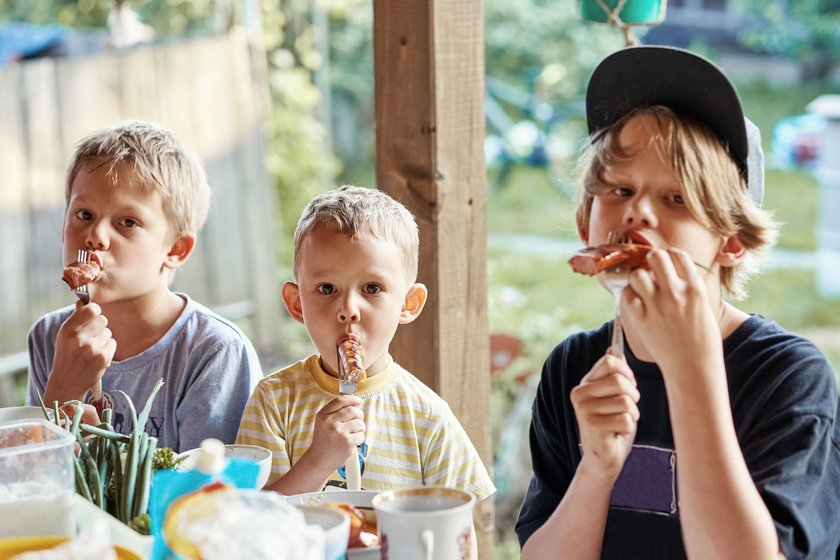 Tischsprüche: Drei Jungs essen Würstchen aufgespießt auf Gabeln