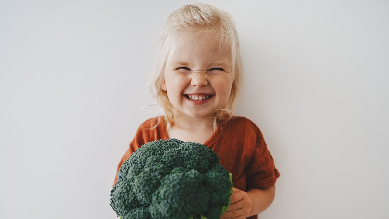 Child girl with broccoli healthy food vegan eating lifestyle organic vegetables plant based diet nutrition funny kid happy smiling