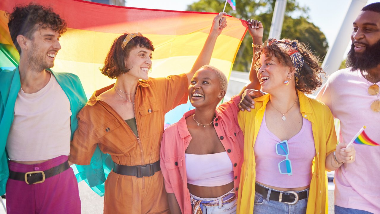 Festival, city and happy lgbt friends with rainbow flag for support, queer celebration and parade for solidarity. Diversity, lgbtq community and people enjoy freedom, happiness and pride identity