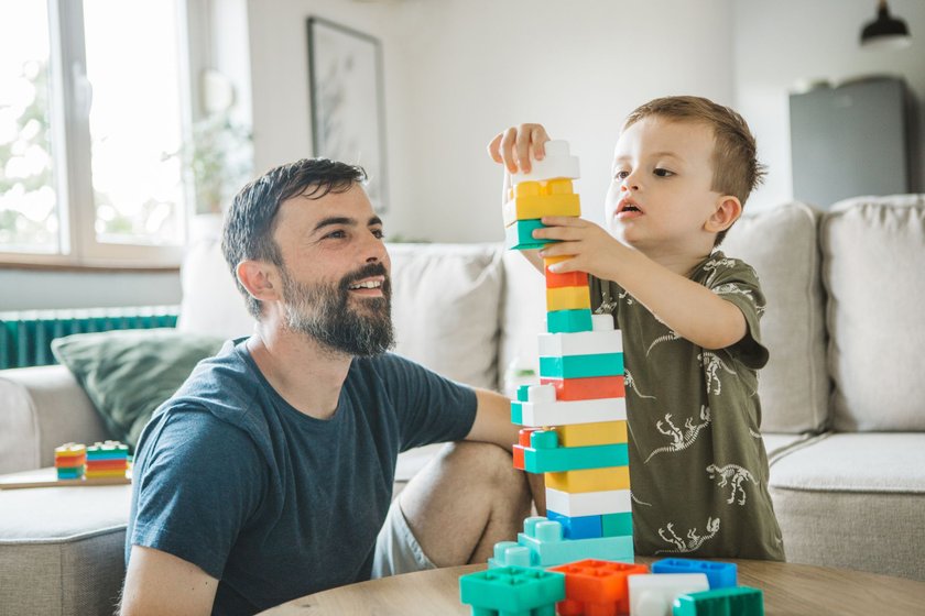 Geschenke für Geschwister zur Geburt: Vater spielt mit Sohn mit Bausteinen