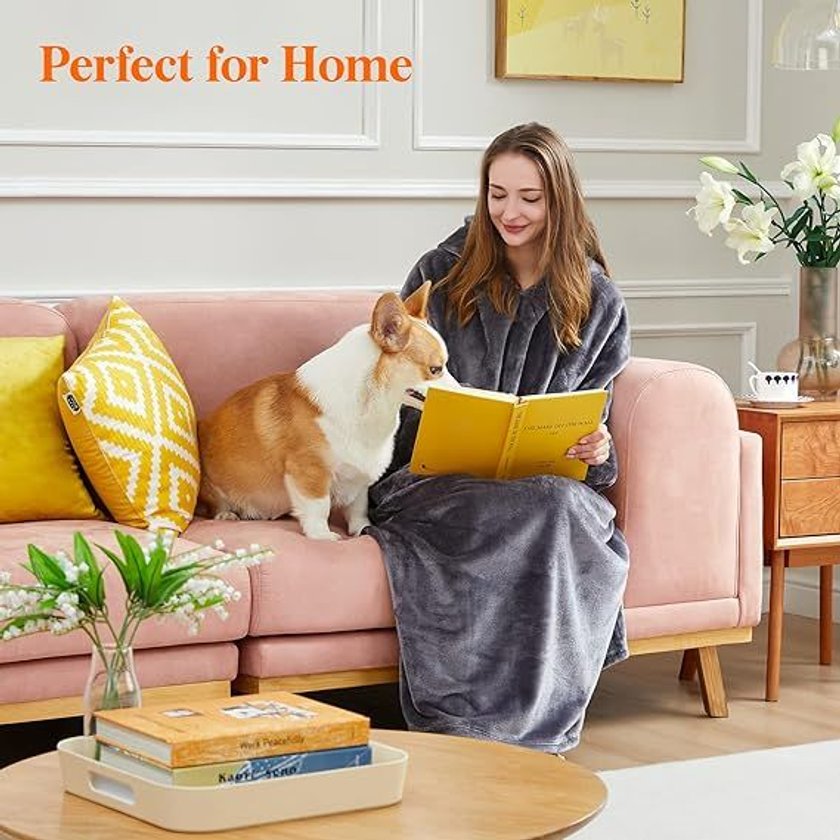 Frau mit tragbarer Hoodie-Decke und Hund auf dem Sofa