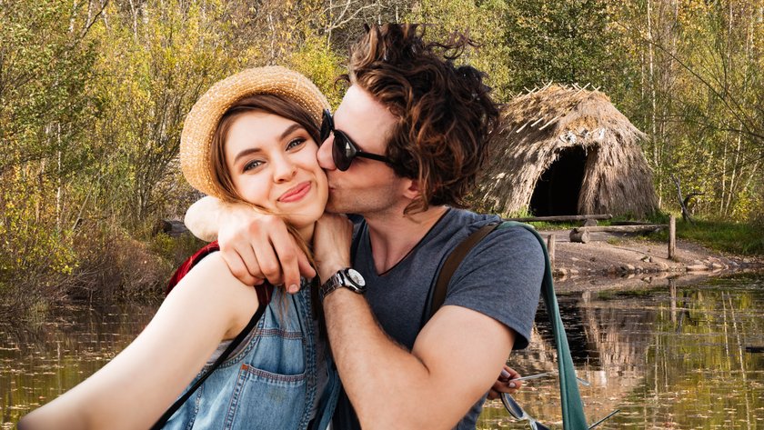 Ein Paar macht ein Selfie vor einer naturbelassenen Hütte