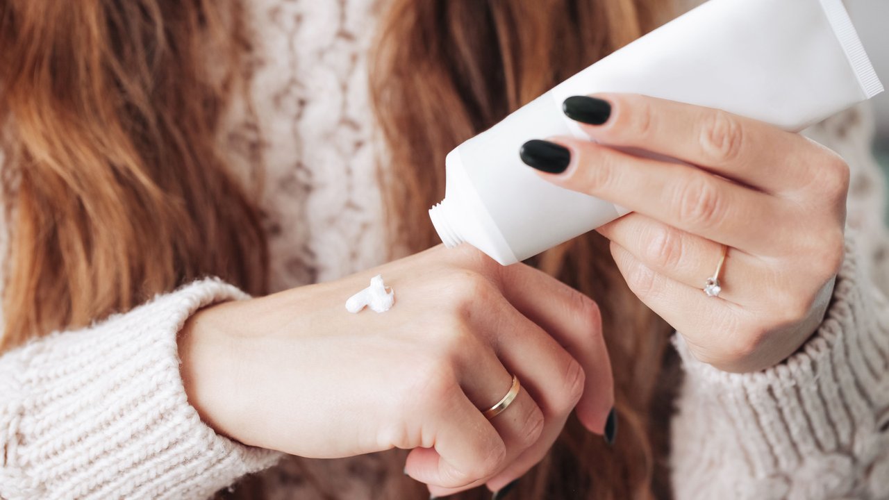 Frau cremt ihre Hände mit Handcreme ein