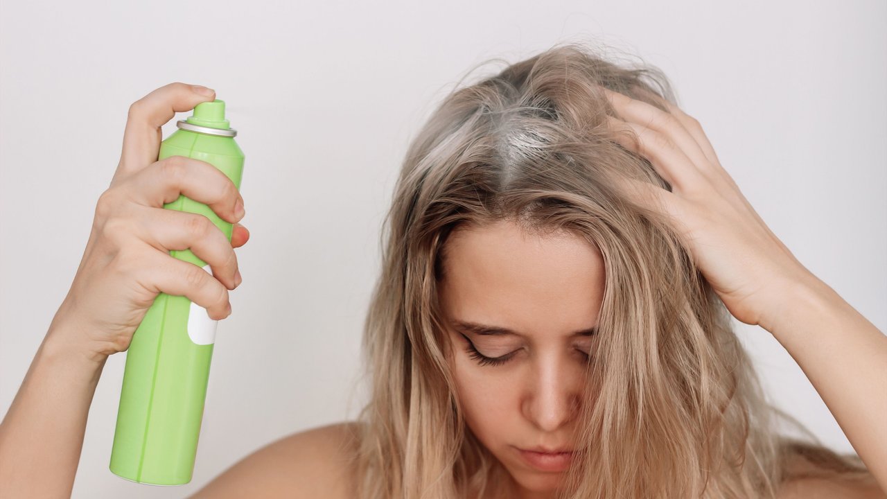 Frau behandelt ihre Haare mit Trockenshampoo