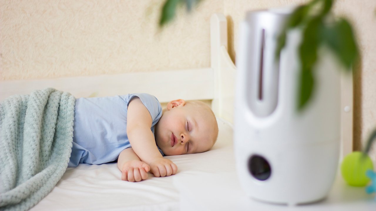 Cute little baby boy sleeping in bedroom with air humidifier. Modern technologies at home. Focus picked.
