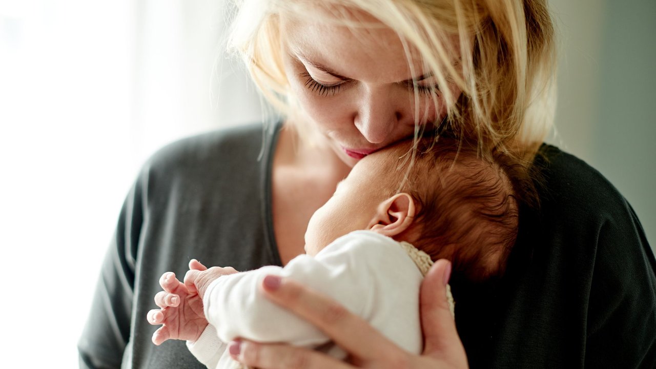 Ab wann kein Frühchen mehr: Mama küsst neugeborenes Baby