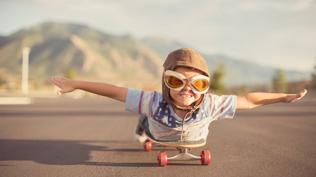 Kind liegt auf skateboard und spiel flugzeug