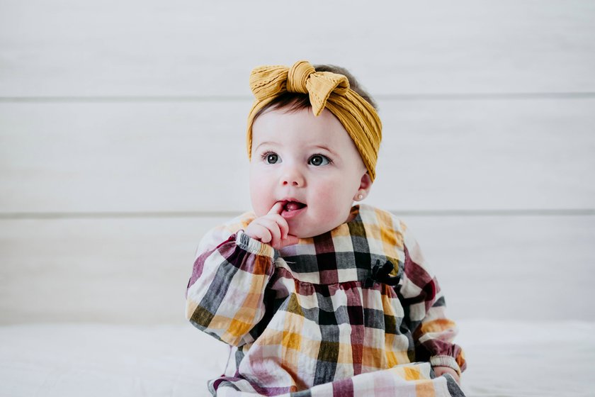 Creative Highlights Symbolbilder Baby girl with finger in mouth sitting on bed at home model released Symbolfoto property released EBBF01059