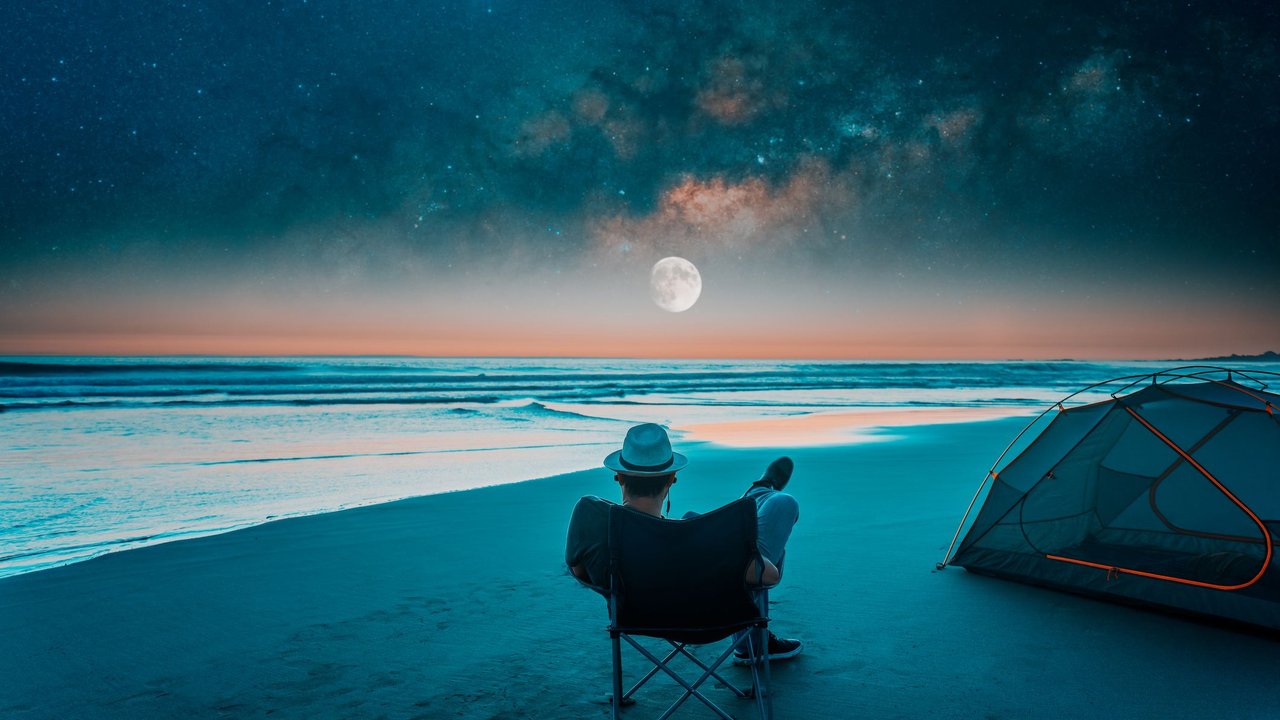 Mann am Strand mit Vollmond über dem Meer