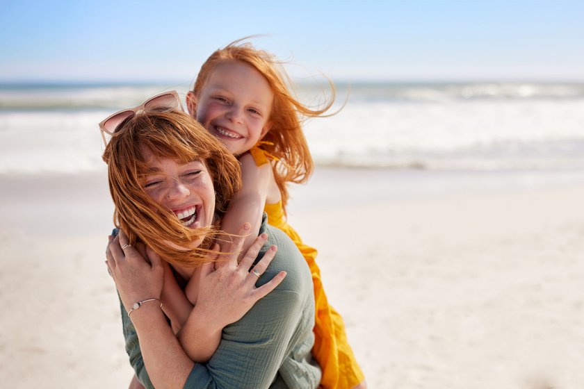 Mutter und Tochter mit roten Haaren lachend am Strand