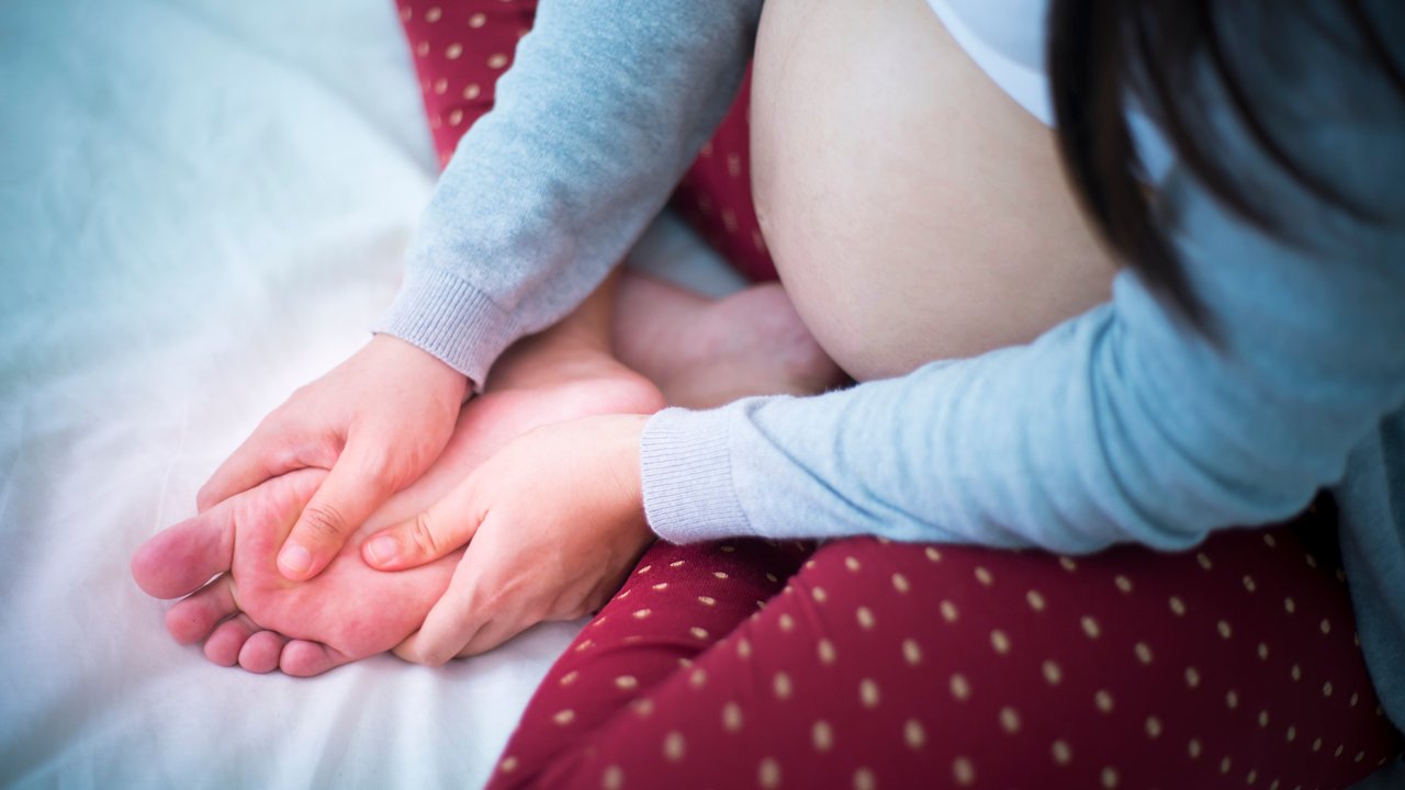 Wassereinlagerungen in der Schwangerschaft: Schwangere massiert geschwollene Füße