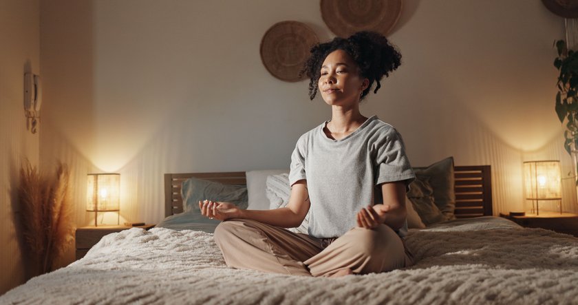 Meditierende Frau auf dem Bett