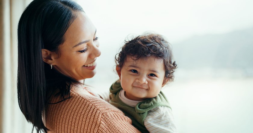 Mother, newborn and smile by window, home and happy together with care, love and bonding in childhood.