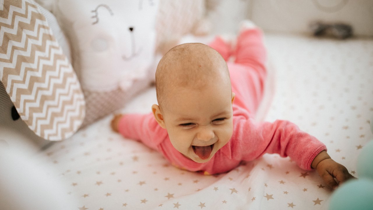 Kleines Baby übt die ersten Krabbelversuche auf einer Krabbeldecke