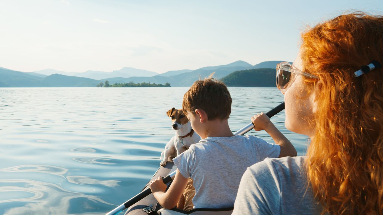 Eine Familie und ihr Hund sitzen in einem Kanu und fahren auf einem See