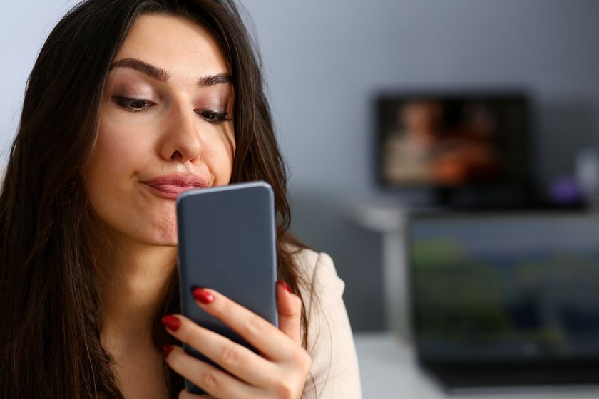 Frau verzieht Gesicht vor dem Handy