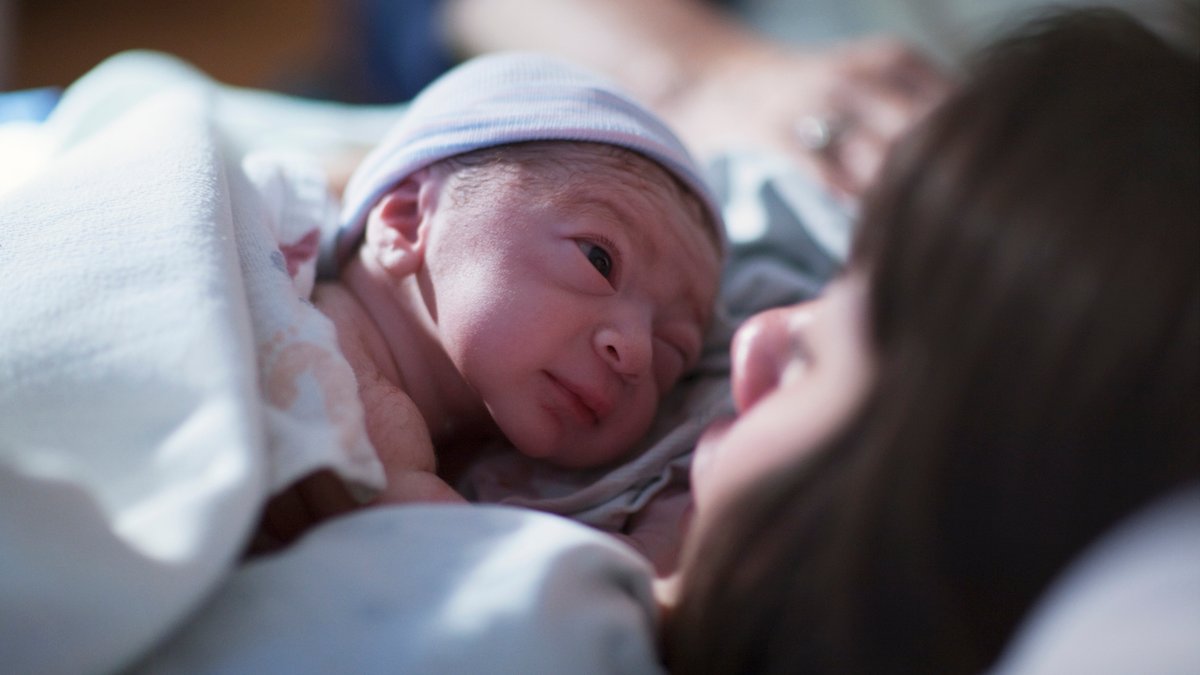 Ein Neugeborenes schaut seine Mutter an