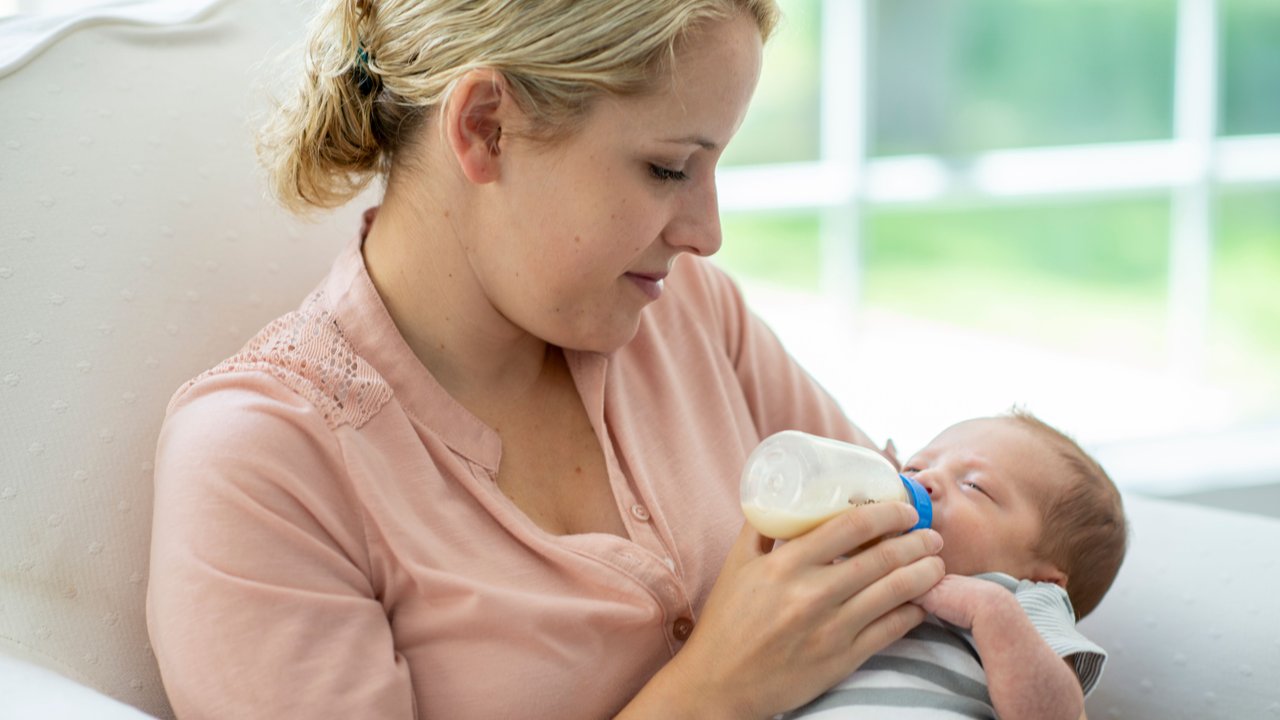 Frau füttert Baby mit Flasche