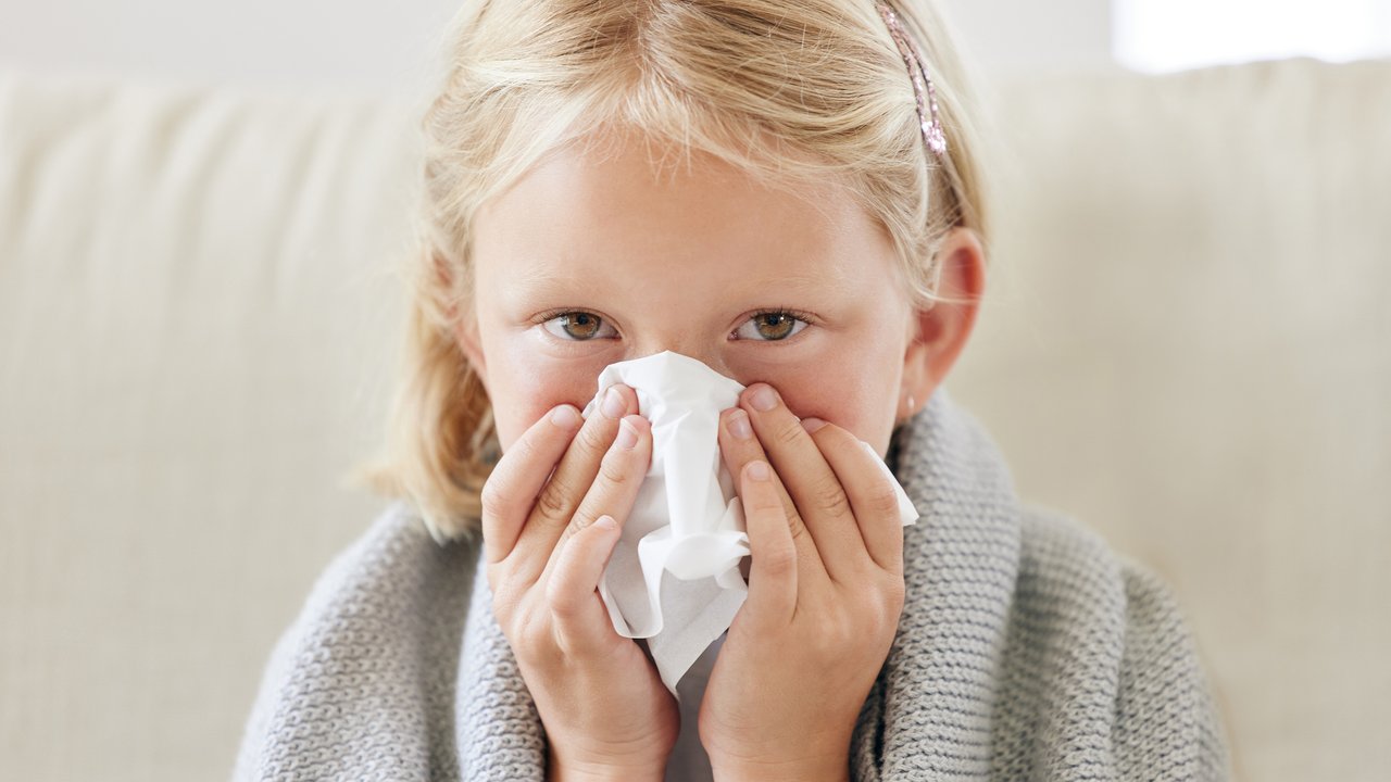 Kind hält sich Taschentuch vor die Nase, weil sie blutet