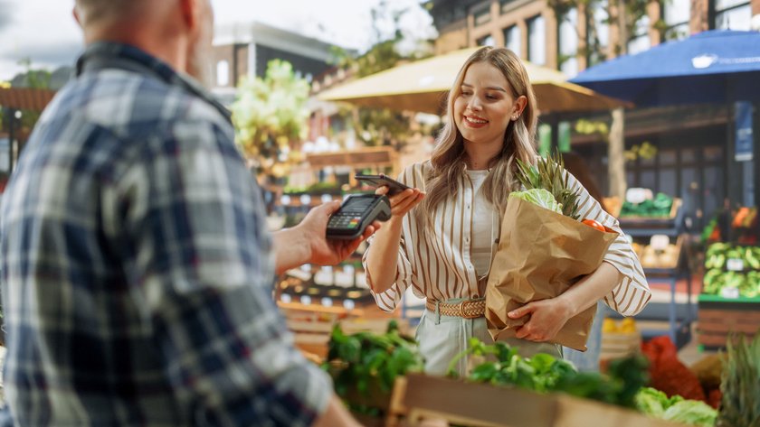 Frau bezahlt Gemüse auf dem Markt