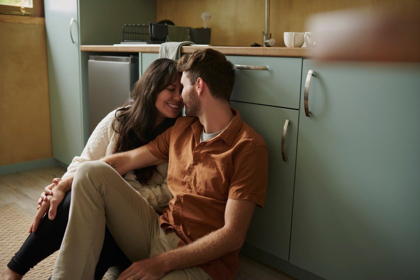 Vertrauen aufbauen: Glückliches Paar sitzt gemeinsam auf dem Küchenboden