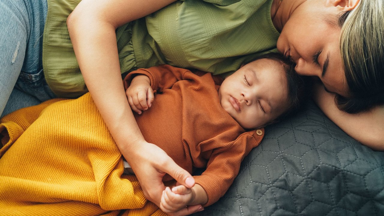 Mutter und Baby liegen schlafend auf dem Sofa
