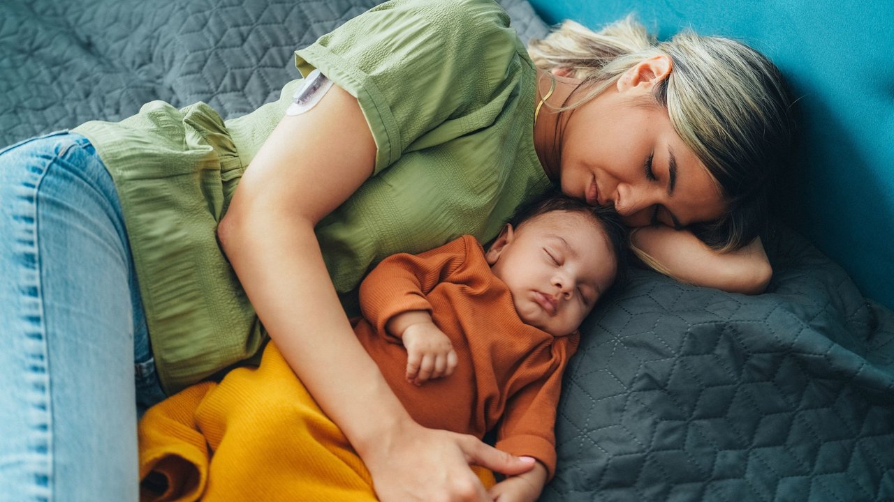 Angst, dass Baby krank wird: Mama kuschelt mit schlafendem Baby