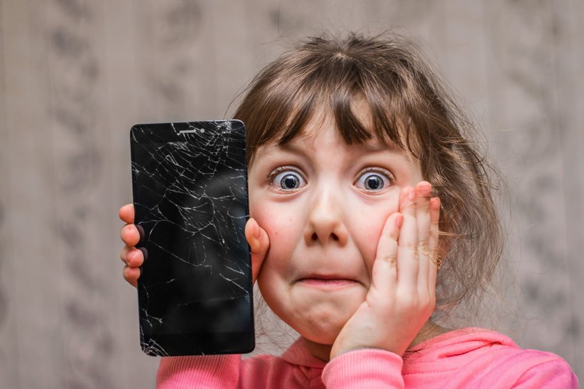 Entsetztes Kind mit kaputtem Handy der Eltern