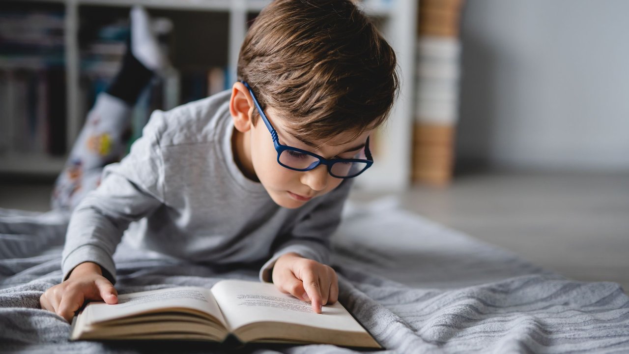 Schlüsselwörter: Kind sucht nach Schlüsselwörtern in seinem Schulbuch.