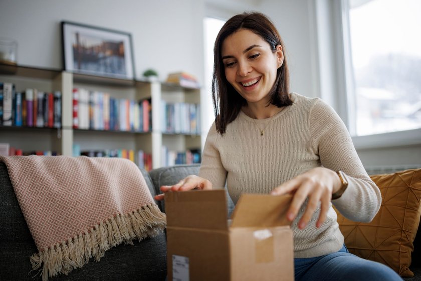 Excited young woman unpacking her latest online delivery at home