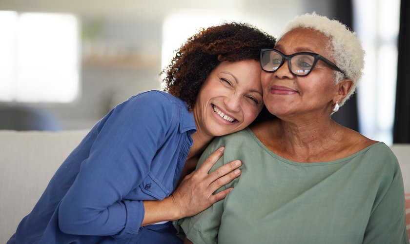 Beziehung zu erwachsenem Kind: Tochter umarmt lachend ihre Mutter