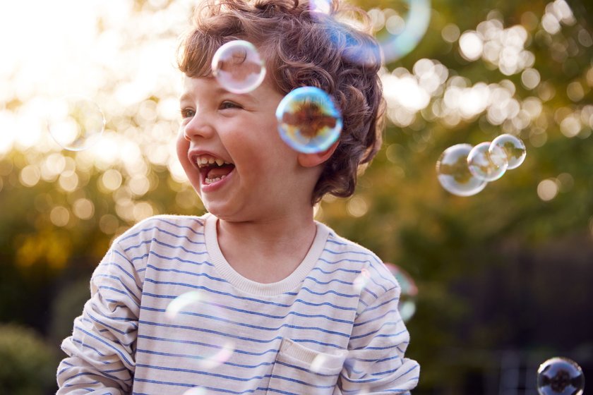 Kleiner Junge spielt im Garten mit Seifenblasen